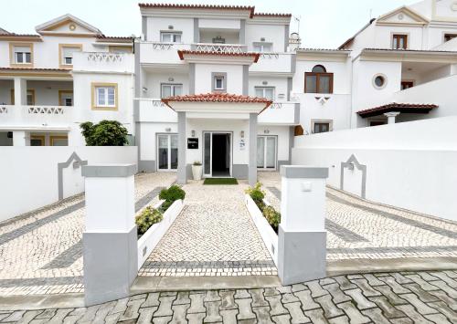a white house with a cobblestone driveway at River Inn - Duna Parque Group in Vila Nova de Milfontes