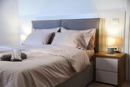 a large bed with white sheets and a blue headboard at Seaside Grand Stay Apartment in Durrës