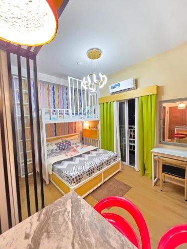 a childs bedroom with green curtains and a table and chairs at MesaCondo Studio with Balcony in Davao City