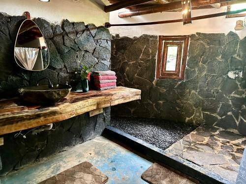a stone bathroom with a sink and a mirror at Eco-Lodge Deseo Bamboo in Santa Catalina