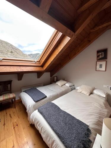 two beds in a room with a large window at Lo somni del riu in Llavorsí