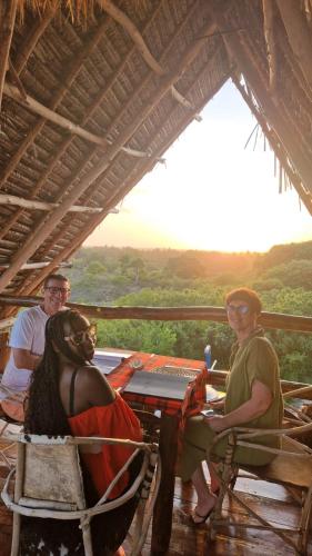 a group of three people sitting at a table at MONKEY MOUNTAIN LODGE in Mtende