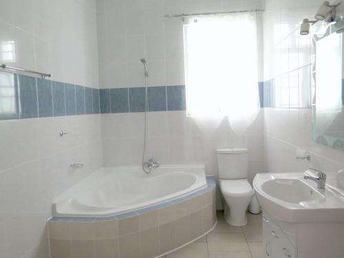 a bathroom with a tub and a toilet and a sink at Hôtel Maisons-Sifa in Butare
