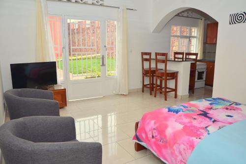 a bedroom with a bed and chairs and a kitchen at Hôtel Maisons-Sifa in Butare
