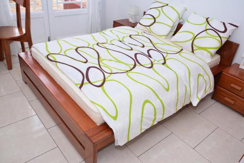 a bed with a yellow and white comforter and pillows at Hôtel Maisons-Sifa in Butare