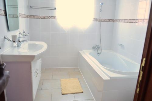 a white bathroom with a tub and a sink at Hôtel Maisons-Sifa in Butare