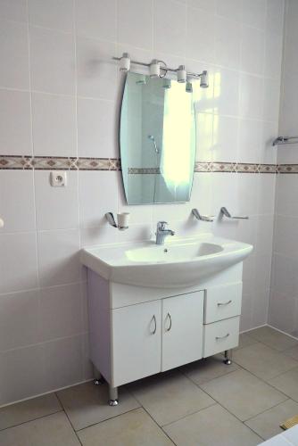 a white bathroom with a sink and a mirror at Hôtel Maisons-Sifa in Butare
