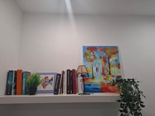 a shelf with books and a painting and a lamp at The Sweet Spot in Torre del Greco
