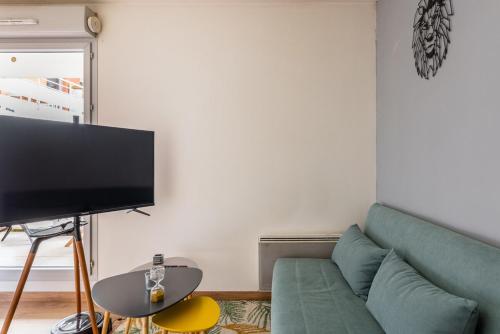 a living room with a green couch and a flat screen tv at JOYAU CACHÉ avec Parking privatif en Hyper-centre in Bourgoin