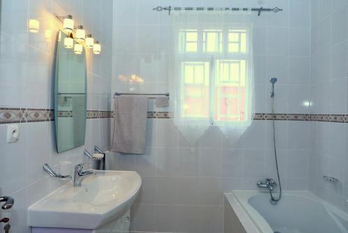 a white bathroom with a sink and a bath tub at Hôtel Maisons-Sifa in Butare