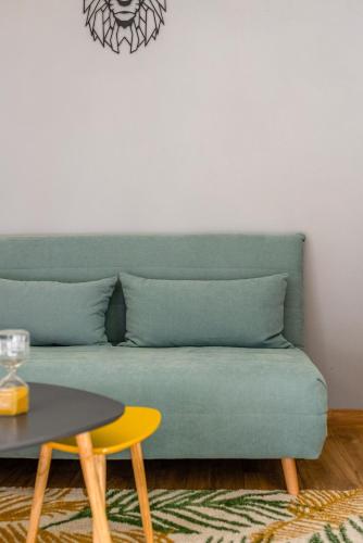 a green couch in a living room with a table at JOYAU CACHÉ avec Parking privatif en Hyper-centre in Bourgoin