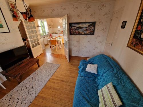 un salon avec un canapé bleu et une télévision dans l'établissement Maison bord de mer, à Hillion