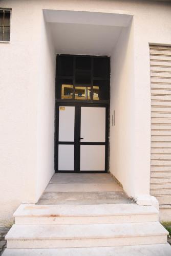 a door in a white building with stairs at Finn Modern Seaside Apartment in Durrës