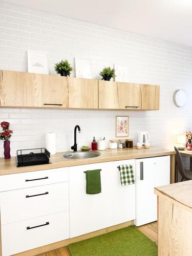 a kitchen with white cabinets and a sink at Apartamenty Prestige Harmony Rosiczkowa in Augustów