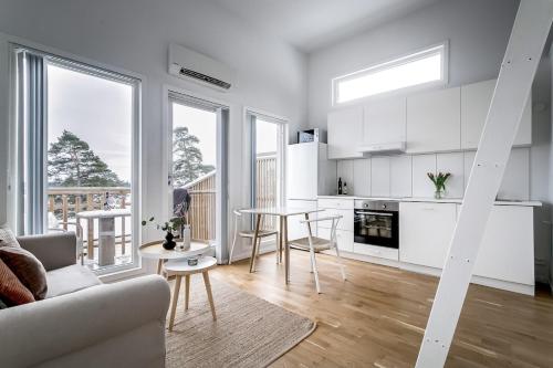 a kitchen and living room with white cabinets and a table at 2x Lake House's-Hot Tub-Stunning View-Private Pier in Smidö
