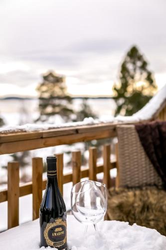 a bottle of wine and a glass on a table at 2x Lake House's-Hot Tub-Stunning View-Private Pier in Smidö