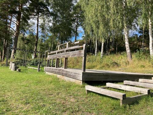 three wooden benches sitting in a field with trees at 2x Lake House's-Hot Tub-Stunning View-Private Pier in Smidö