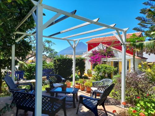 a patio with chairs and tables and a pergola at Cottage at FLAMINGAS PLACE in Lajes do Pico