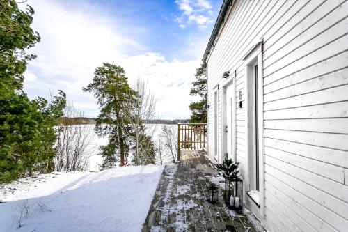 a white house with snow on the side of it at 2x Lake House's-Hot Tub-Stunning View-Private Pier in Smidö