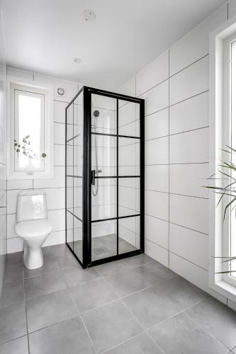 a bathroom with a toilet and a glass door at 2x Lake House's-Hot Tub-Stunning View-Private Pier in Smidö