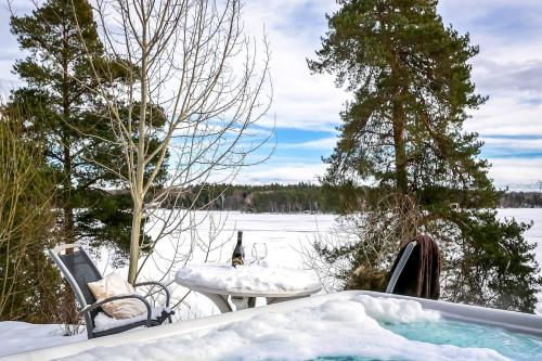 a hot tub in the snow with a bottle of wine at 2x Lake House's-Hot Tub-Stunning View-Private Pier in Smidö