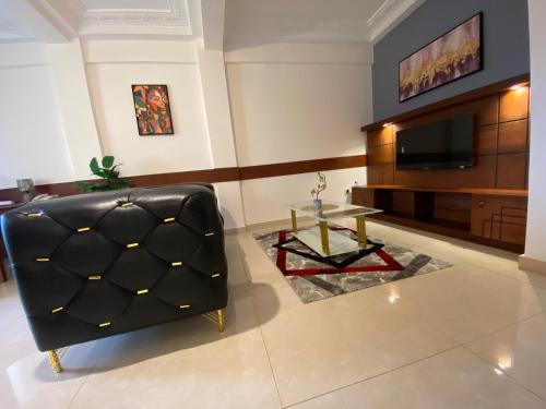 a living room with a black leather chair and a table at Résidence hôtelière MEDOM Palace, Bastos in Yaoundé