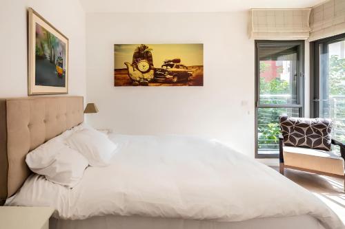 a bedroom with a large white bed and a chair at Luxury Oasis Tel Aviv Beach in Tel Aviv
