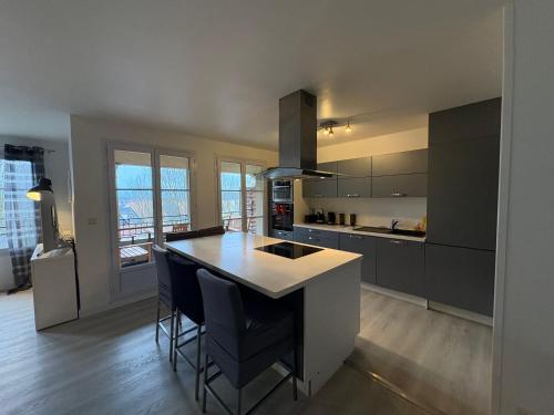 une cuisine avec un comptoir et un îlot de cuisine avec des chaises dans l'établissement T5 Disney Paris/Val d’Europe, à Serris