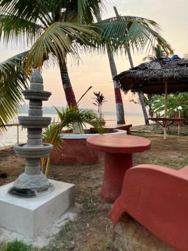 a resort with a table and a bench and palm trees at Lake Homes in Varkala