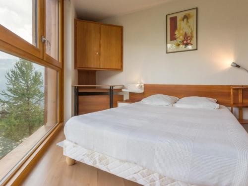 une chambre avec un grand lit blanc et une fenêtre dans l'établissement Appartement cosy près des pistes avec WIFI gratuit - FR-1-275-145, à Montvalezan