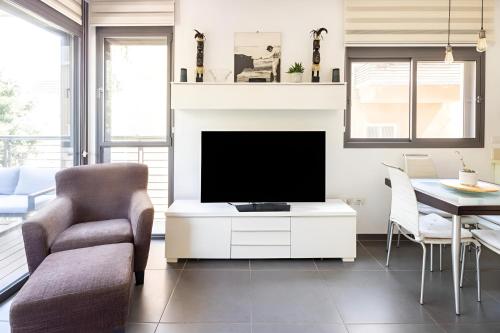 a living room with a tv and a chair and a table at Luxury Oasis Tel Aviv Beach in Tel Aviv