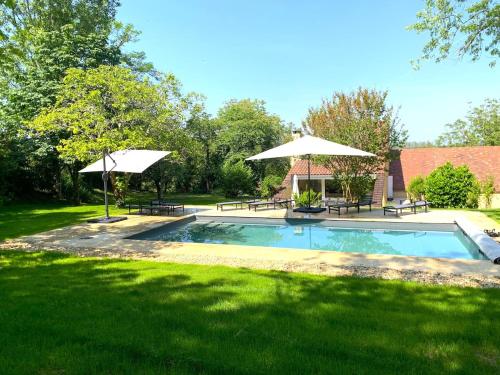 - une piscine avec 2 tables et des parasols dans l'établissement BEYTAN AL COUDER Stylish architect house with AC and private pool, village center, golf course and Dordogne river at easy walk, à Siorac-en-Périgord