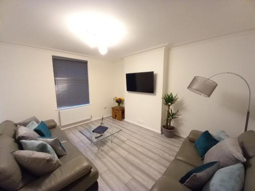 a living room with two couches and a television at Modern and Luxurious 4 bedroom house in Bangor