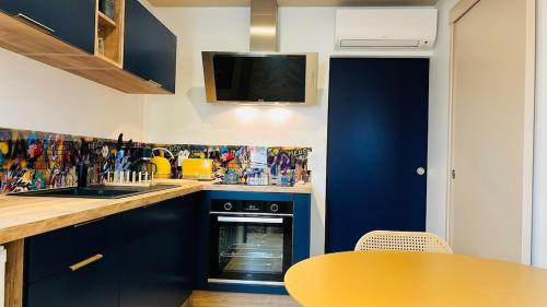 eine Küche mit blauen Schränken, einem Tisch und einem TV in der Unterkunft T2 neuf centre ville la tour du pin-Clim-parking-gare in La Tour-du-Pin