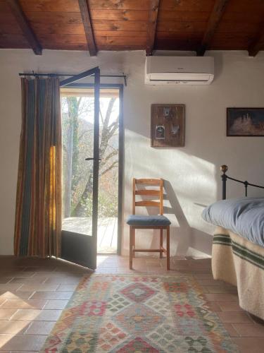 a bedroom with a bed and a chair and a window at Umbrian cottage retreat in San Giovanni del Pantano