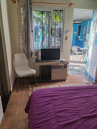 a bedroom with a bed and a desk and a chair at Apto independiente al fondo de casa familiar in Montevideo