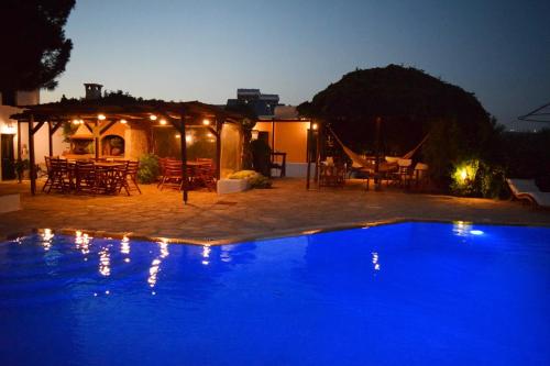 a large blue swimming pool in a yard at night at Tzane Studios & Apartments - Steps away from Golden Beach in Chrissi Akti