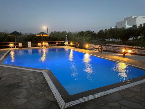 a large swimming pool with blue water at night at Tzane Studios & Apartments - Steps away from Golden Beach in Chrissi Akti
