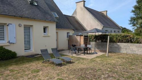 a house with a table and chairs and an umbrella at L'appart le “BapTho” in Cléder