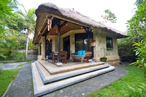 mały domek z dachem krytym strzechą w obiekcie Sama's Cottages and Villas w mieście Ubud