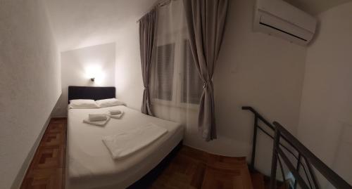 a small bedroom with a white bed and a window at App Paula1 in Trogir
