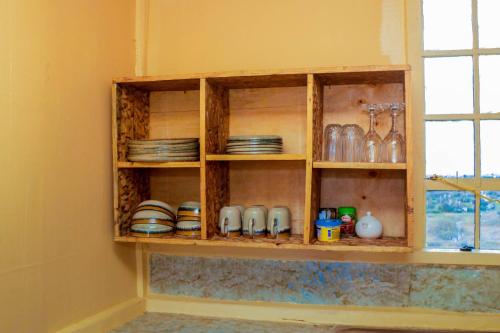 a kitchen shelf with plates and dishes on it at Amanya 2-Bedroom Self Catering Tent in Amboseli