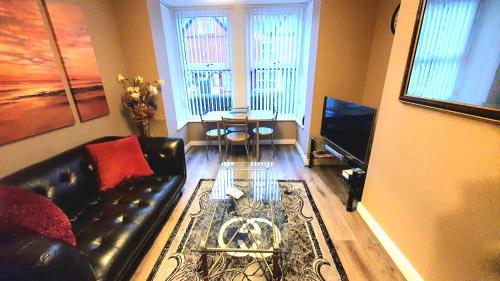 a living room with a black leather couch and a television at The Savile - Luxury Apartment Leeds - Your Next Stay in Leeds