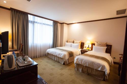 Habitación de hotel con 2 camas y TV en Rich Garden Hotel, en Taipéi