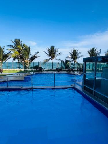 a blue swimming pool with palm trees in the background at Cobertura Duplex Pé na Areia 509 Tabatinga Residence in Conde
