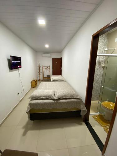 Un dormitorio con una cama y un televisor en la pared. en Recando Dourado Suíte 4, en São Miguel dos Milagres