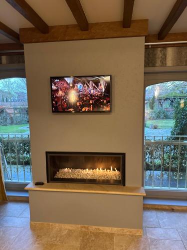 a fireplace in a living room with a tv above it at B&B De Rentmeesterhoeve in Reningelst