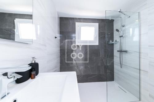 une salle de bain blanche avec une douche et un lavabo dans l'établissement Infinity Blue Luxury Flat by OYOOSTAYS, à Torrevieja