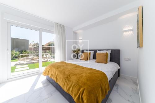 une chambre blanche avec un lit et une grande fenêtre dans l'établissement Infinity Blue Luxury Flat by OYOOSTAYS, à Torrevieja