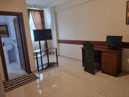 a hotel room with a desk and a television at Résidence hôtelière MEDOM Palace, Bastos in Yaoundé